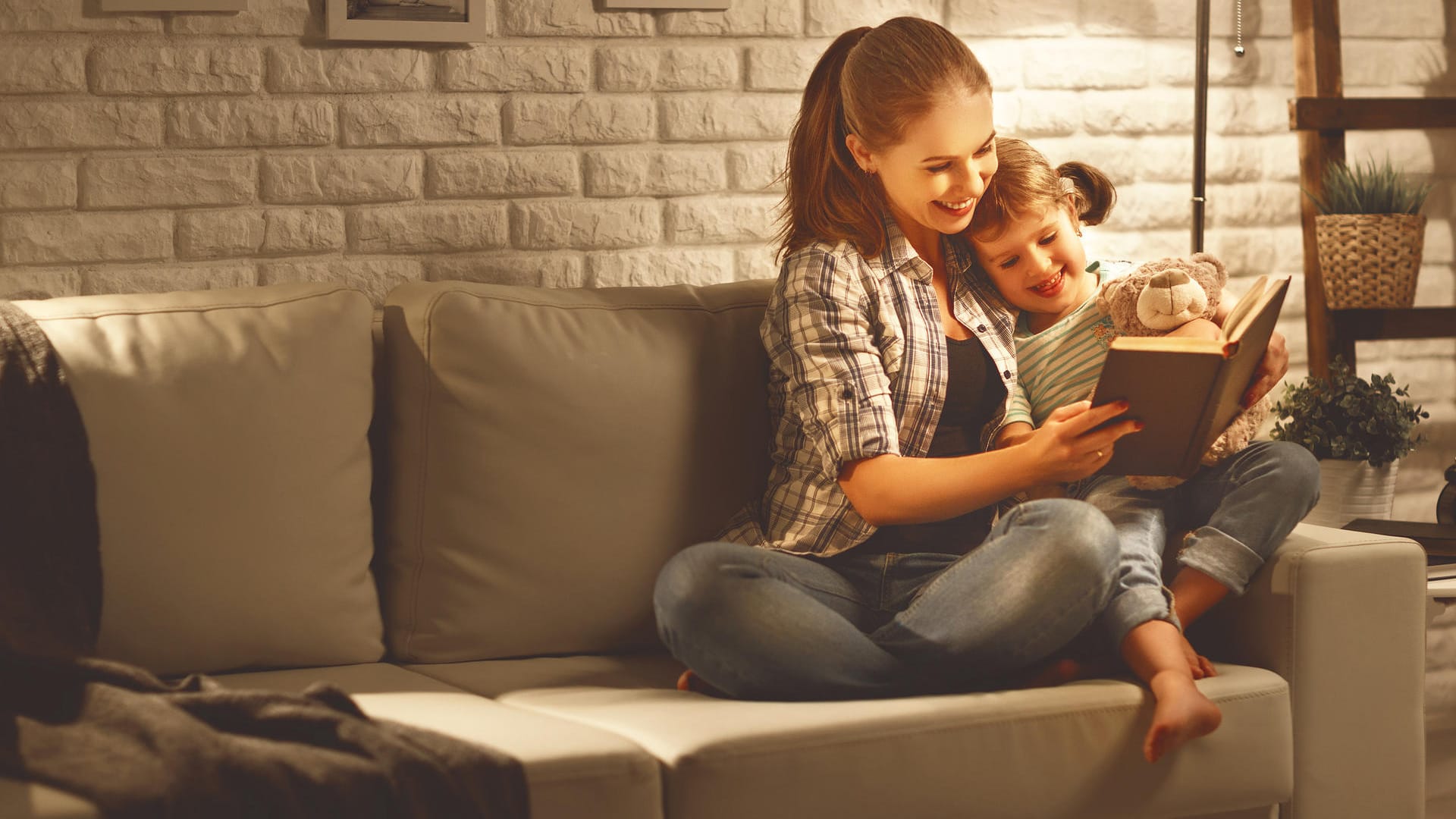 Mutter und Tochter schauen in ein Buch: Wenn ein Kind lesen lernt, wird im Gehirn einiges umstrukturiert.