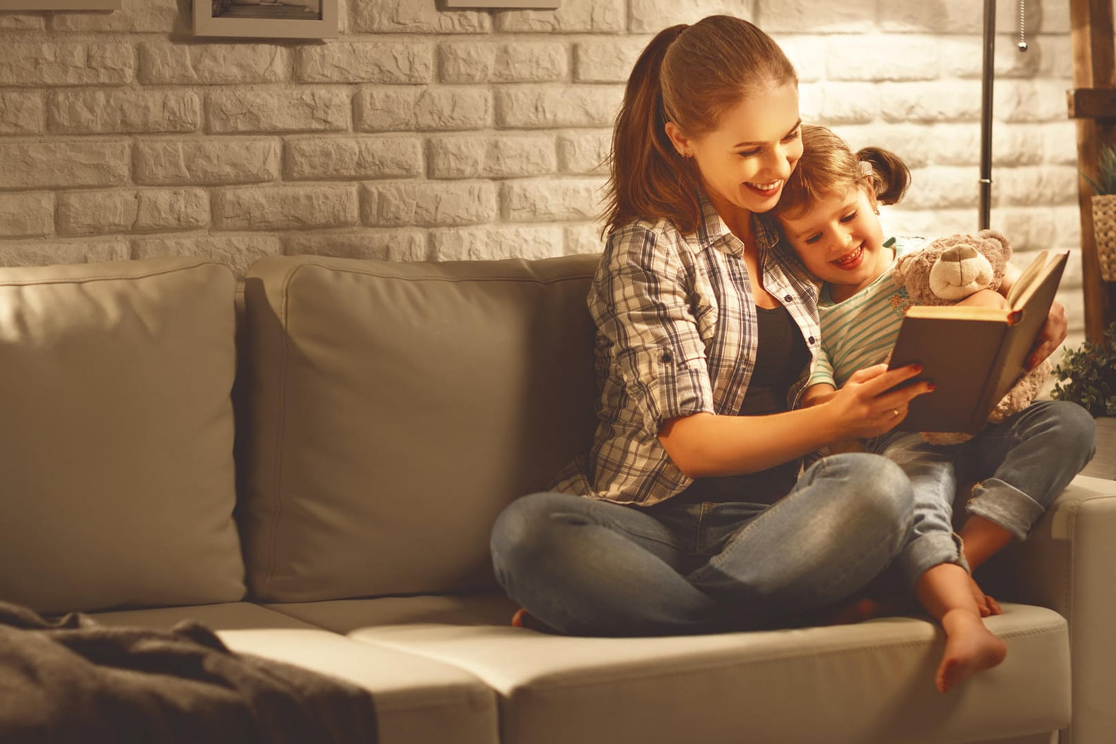 Mutter und Tochter schauen in ein Buch: Wenn ein Kind lesen lernt, wird im Gehirn einiges umstrukturiert.