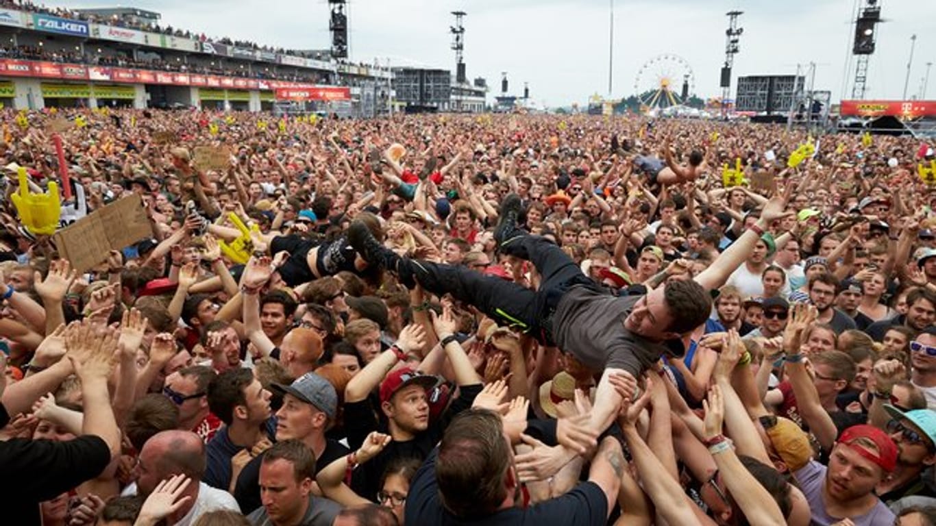 Crowdsurfer lassen sich in Nürburg vor der Hauptbühne des Musikfestivals Rock am Ring während des Auftritts der Band "Broilers" über die Köpfe des Publikums tragen.