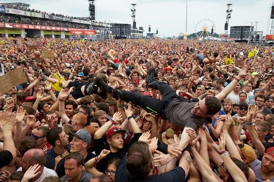 Crowdsurfer lassen sich in Nürburg vor der Hauptbühne des Musikfestivals Rock am Ring während des Auftritts der Band "Broilers" über die Köpfe des Publikums tragen.