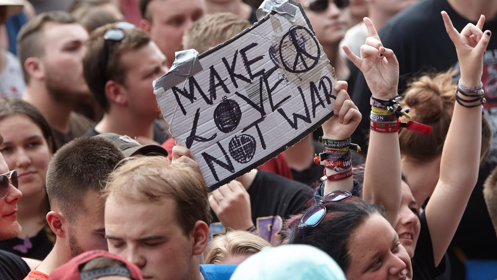 Rockfans halten beim Musikfestival "Rock am Ring" ein Schild mit der Aufschrift "Make love not war" hoch. Rockfans halten beim Musikfestival "Rock am Ring" ein Schild mit der Aufschrift "Make love not war" hoch.