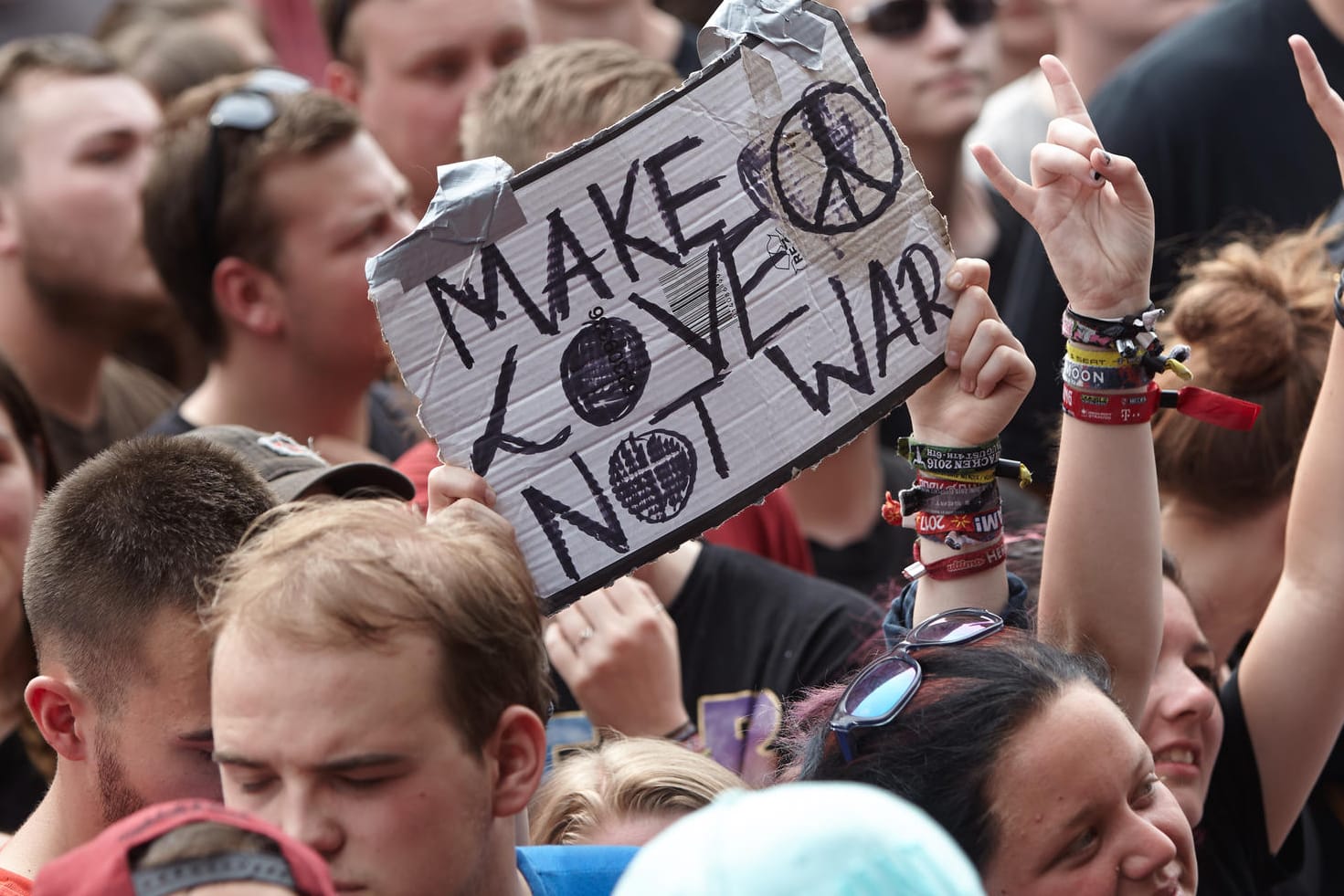 Rockfans halten beim Musikfestival "Rock am Ring" ein Schild mit der Aufschrift "Make love not war" hoch.