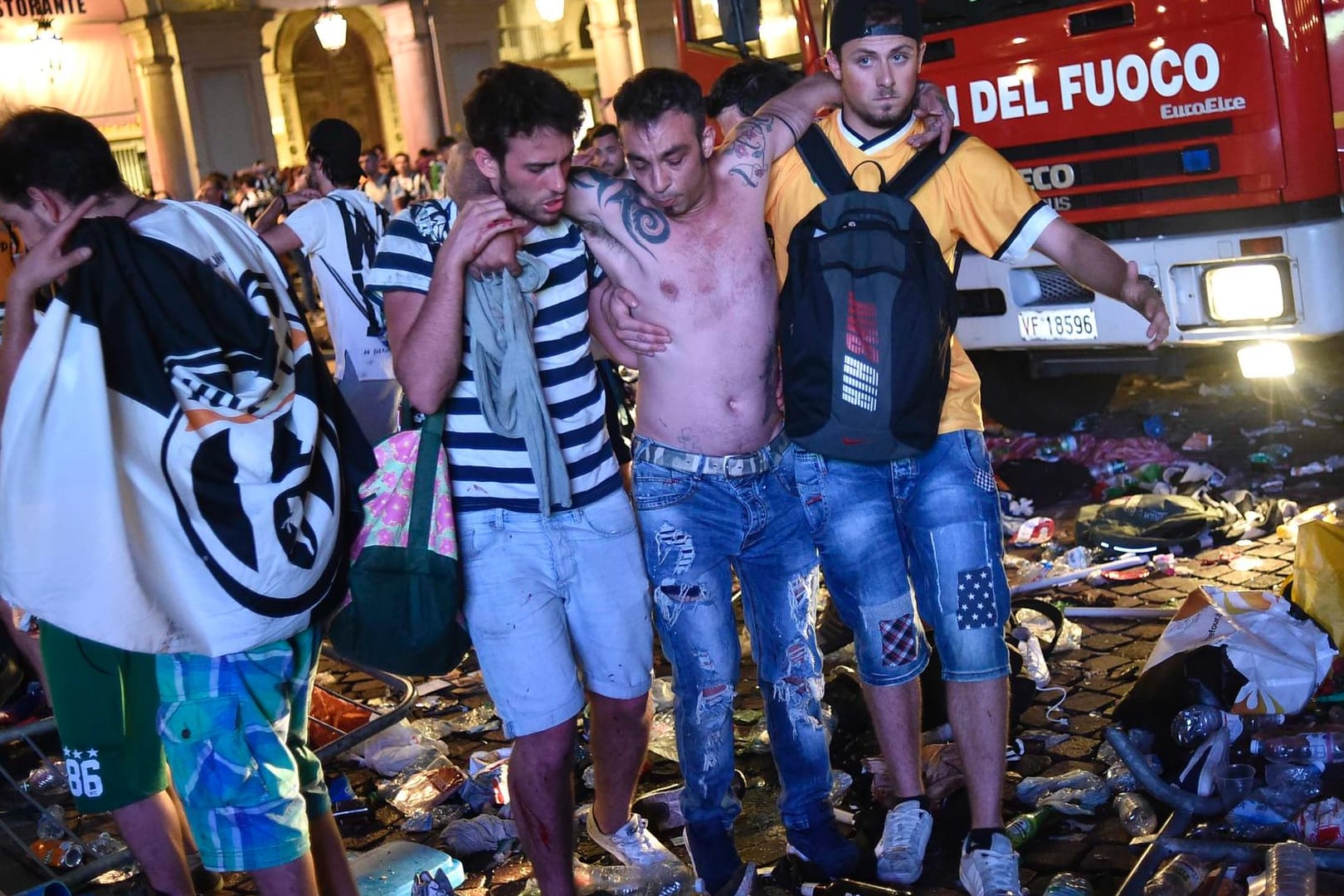 Zwei Männer stützen einen Verletzten am San Carlo Square.