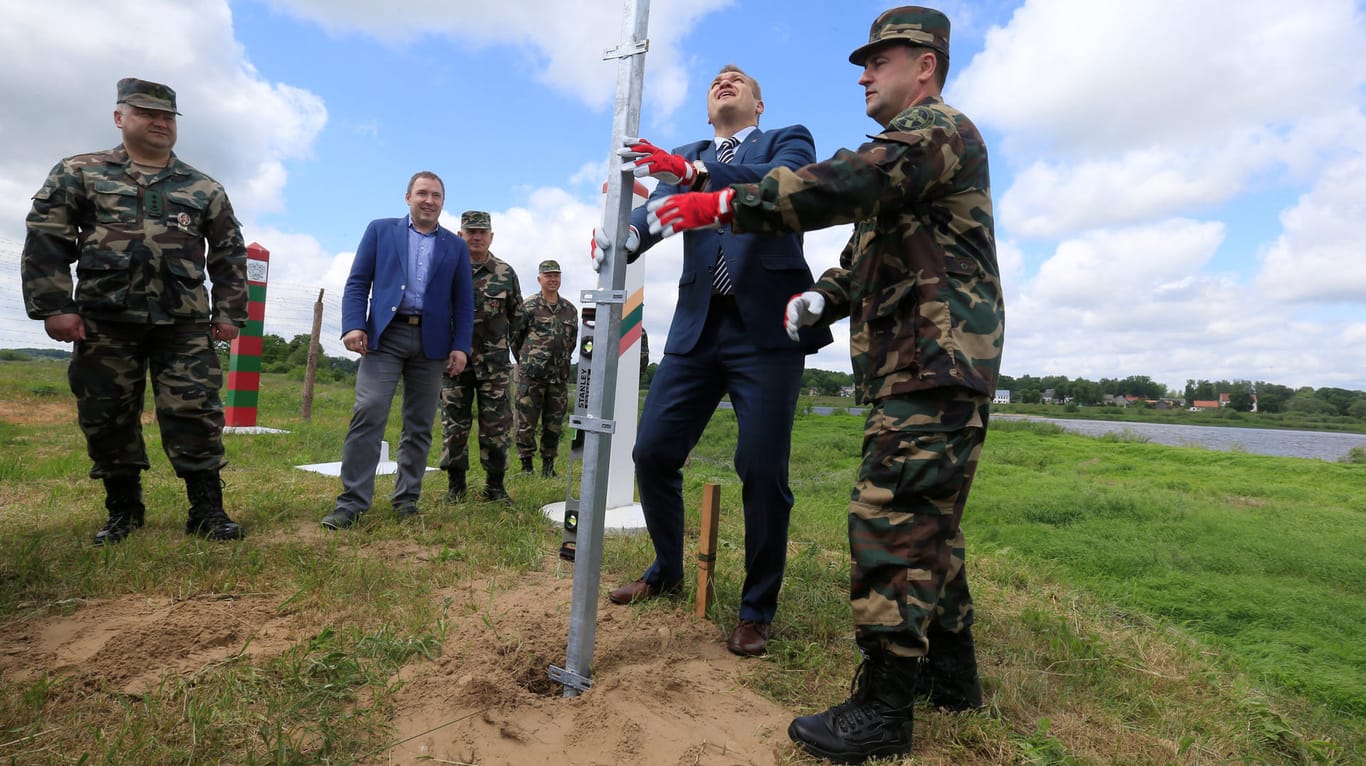 Der Kommandant des litauischen Staatsgrenzenschutzes Pozela und Innenminister Misiunas installierieren den ersten Pfosten des neuen Zauns.