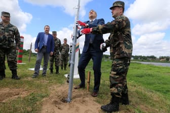 Der Kommandant des litauischen Staatsgrenzenschutzes Pozela und Innenminister Misiunas installierieren den ersten Pfosten des neuen Zauns.