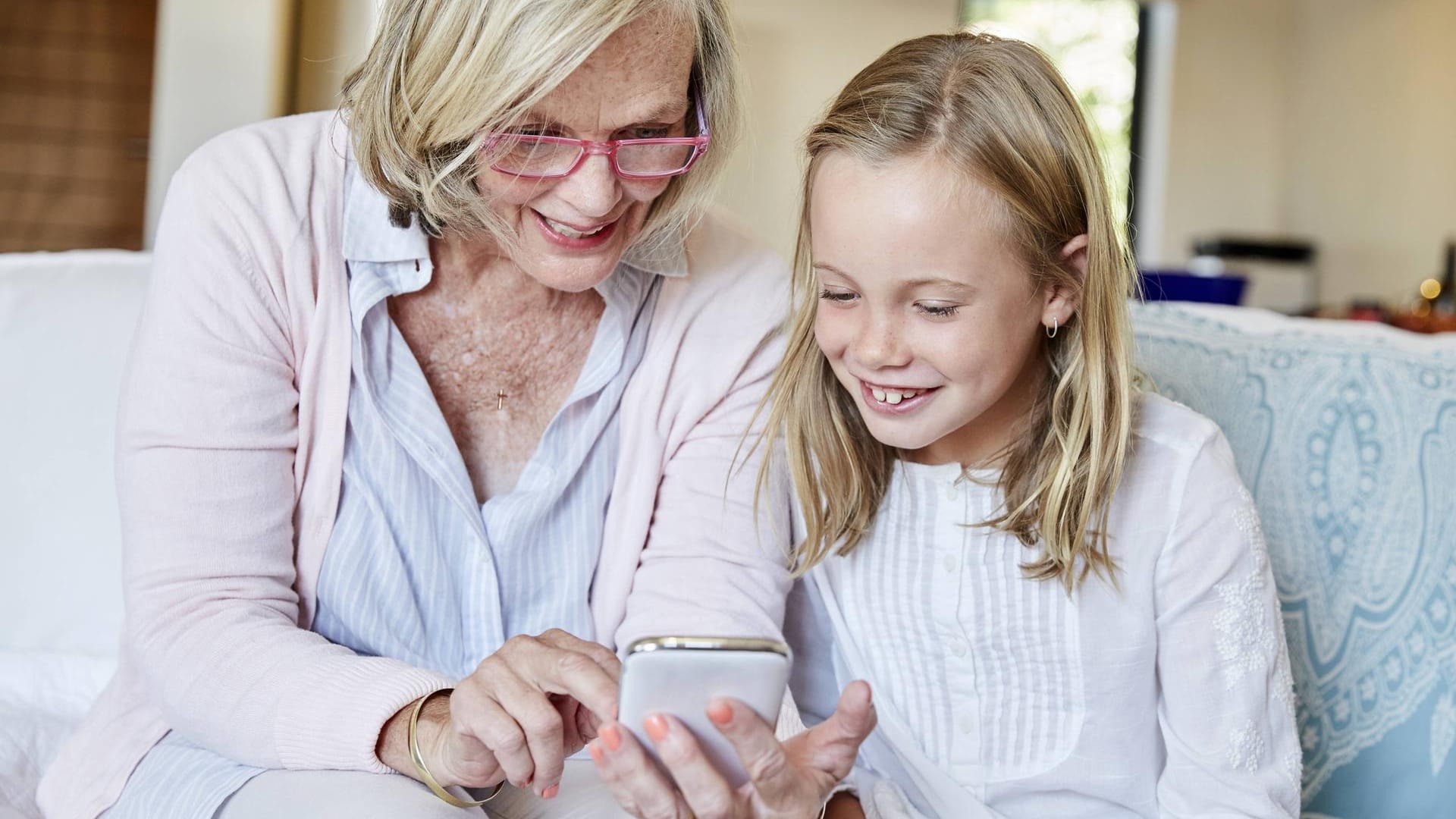 Großmutter und Enkelin nutzen gemeinsam ein Smartphone