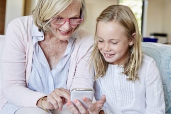 Großmutter und Enkelin nutzen gemeinsam ein Smartphone