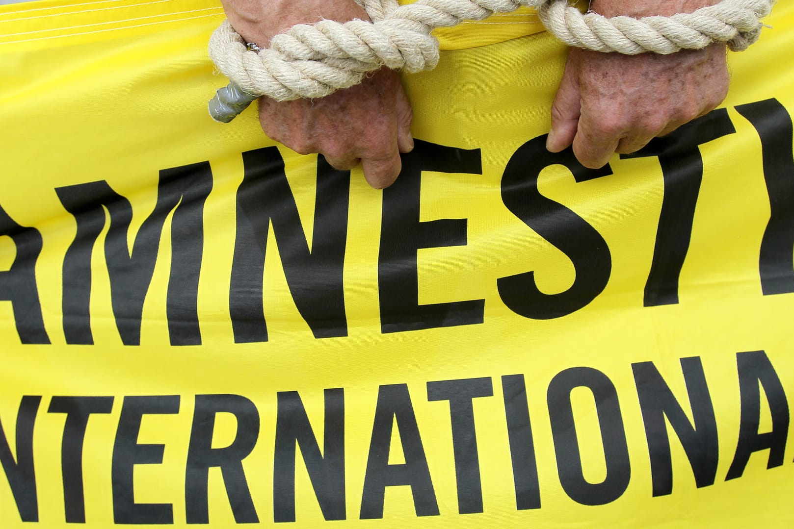 Ein Aktivist von Amnesty International mit symbolischen Fesseln.