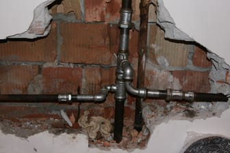 Ein freigelegtes Rohr: Häufig müssen Handwerker bei einem Rohrbruch die Wand aufstemmen – das kann teuer werden.