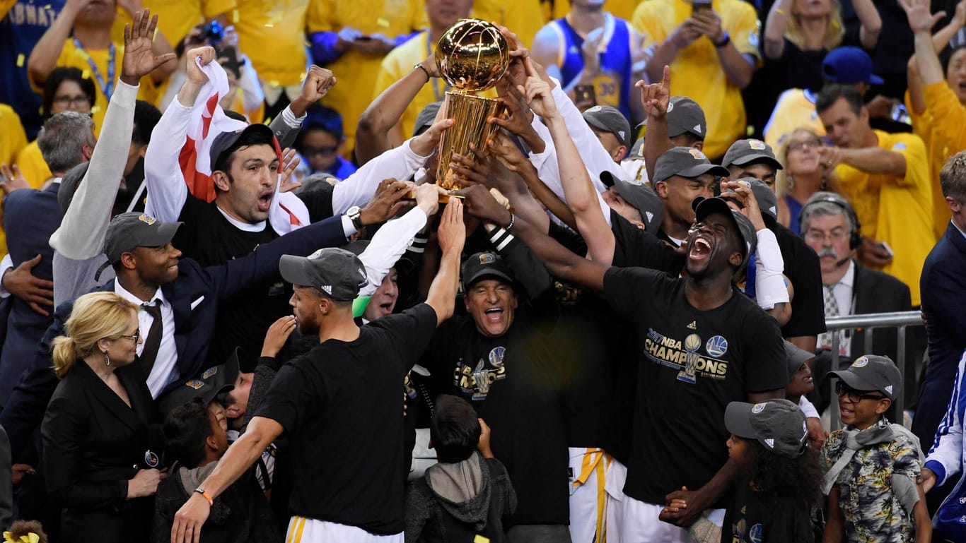Spieler und Trainer der Golden State Warriors stemmen die NBA-Trophäe in die Luft.