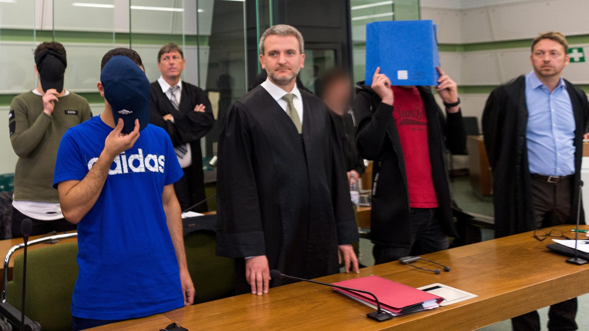 Vier der sechs Männer, die sich wegen gemeinschaftlichen versuchten Mordes verantworten müssen, stehen mit ihren Anwälten im Sitzungssaal des Berliner Landgerichtes. Vier der sechs Männer, die sich wegen gemeinschaftlichen versuchten Mordes verantworten müssen, stehen mit ihren Anwälten im Sitzungssaal des Berliner Landgerichtes.