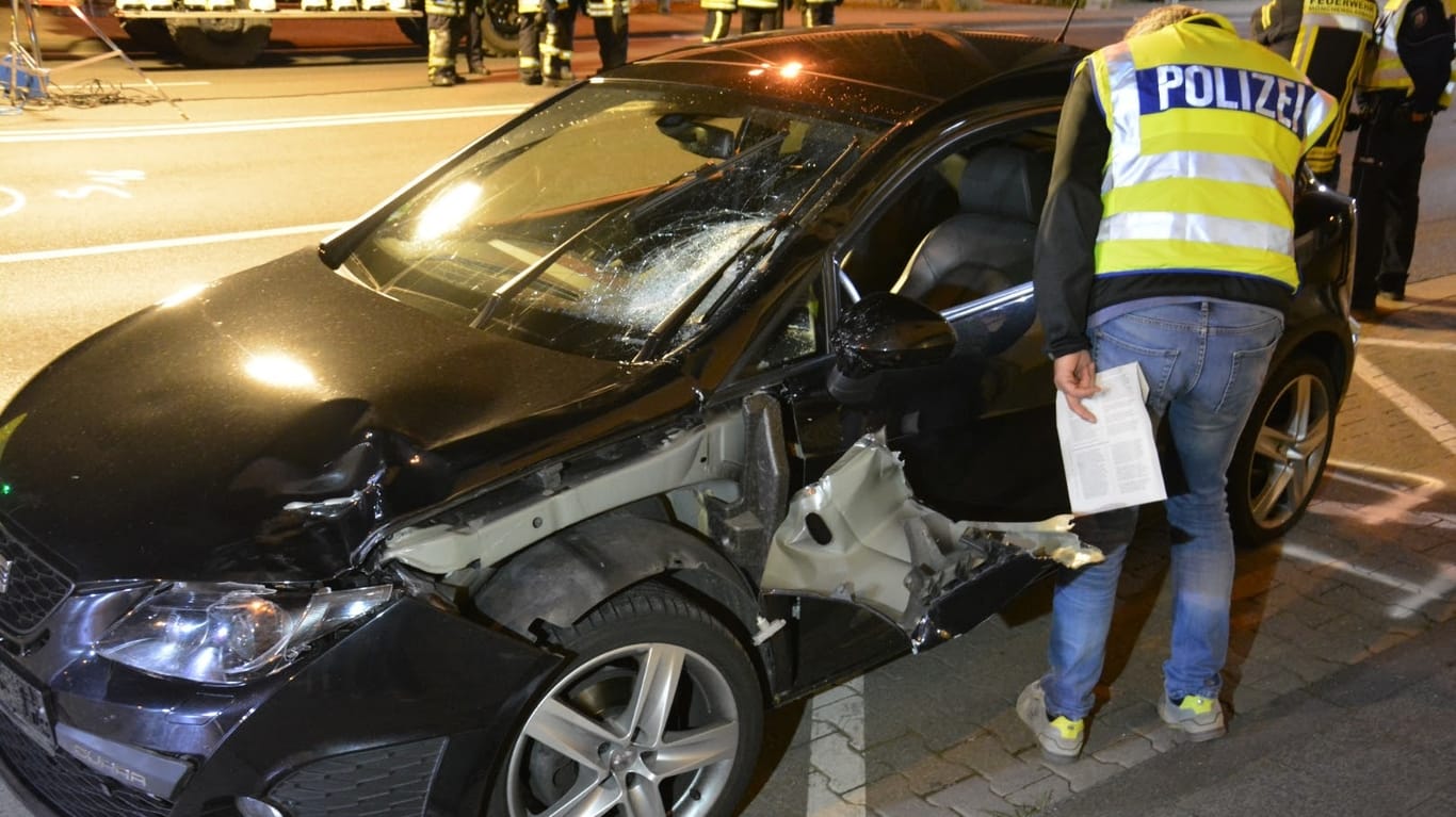Ein Polizist untersucht in der Nacht das Autowrack an der Unfallstelle in Mönchengladbach.