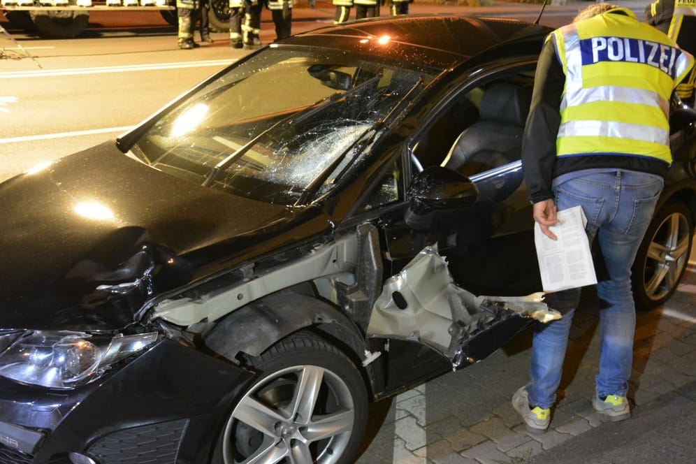 Ein Polizist untersucht in der Nacht das Autowrack an der Unfallstelle in Mönchengladbach.