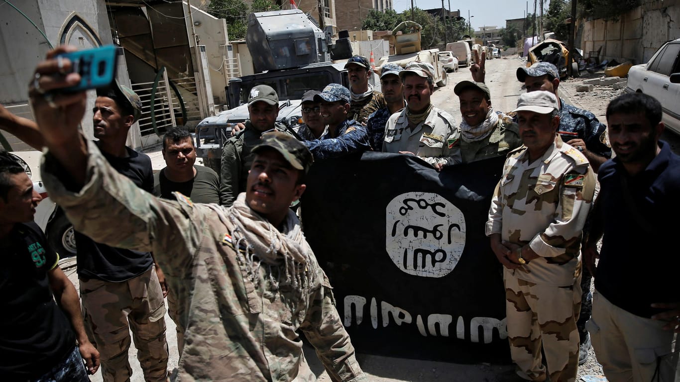 Irakische Truppen posieren mit einer erbeuteten IS-Flagge als "Trophäe" in Mossul.