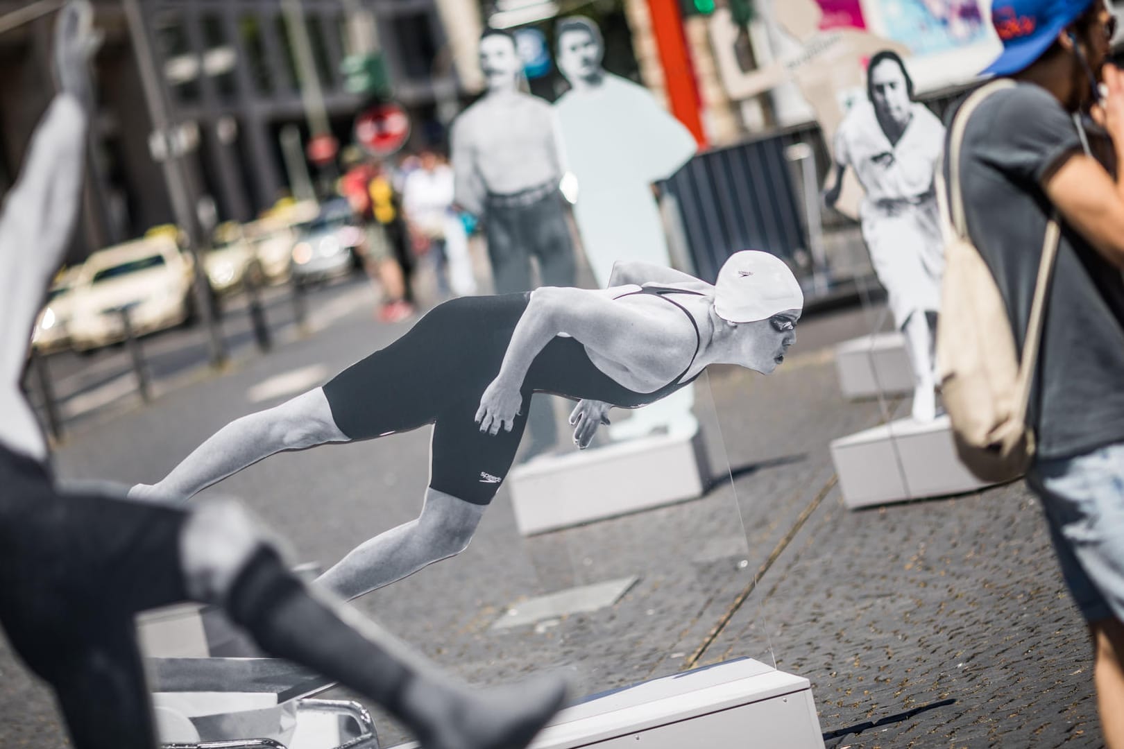 Ein Passant steht auf dem Rathenauplatz in Frankfurt am Main vor einem lebensgroßen Bild der Schwimmerin Sarah Poewe (M), der ersten jüdischen Athletin, die nach dem Ende des Zweiten Weltkrieges eine olympische Medaille für Deutschland errang. Die Freiluft-Ausstellung läuft unter dem Titel "Zwischen Erfolg und Verfolgung. Jüdische Stars im deutschen Sport bis 1933 und danach"