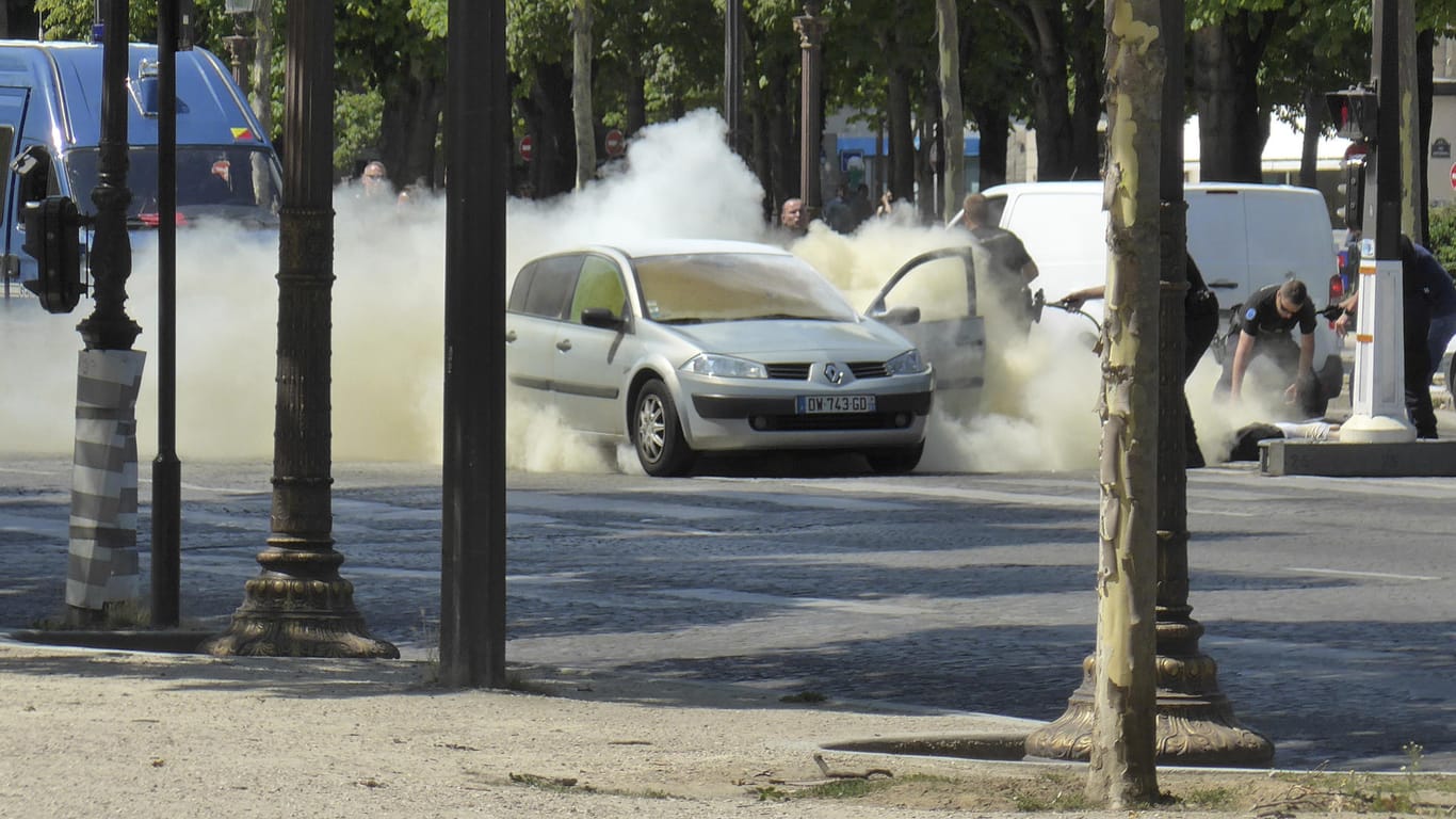 Polizisten löschen auf den Champs Elysees in Paris das Auto, mit dem Mann zuvor ein Fahrzeug der französischen Gendarmerie gerammt hatte.