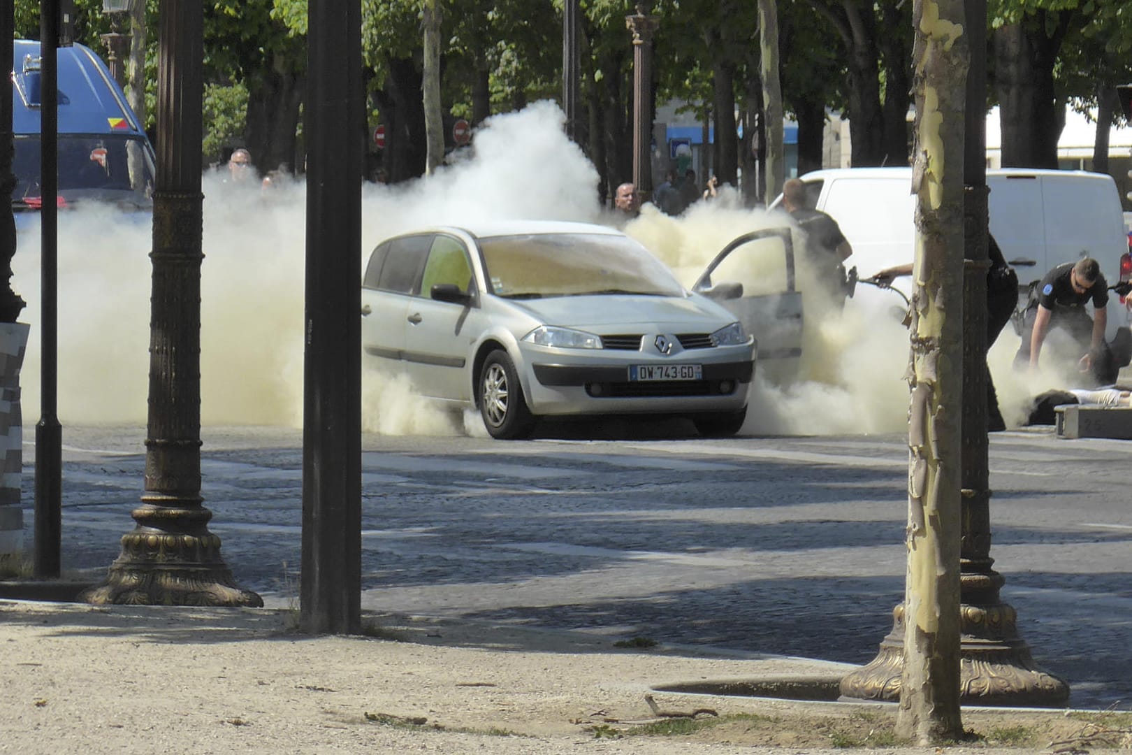 Polizisten löschen auf den Champs Elysees in Paris das Auto, mit dem Mann zuvor ein Fahrzeug der französischen Gendarmerie gerammt hatte.