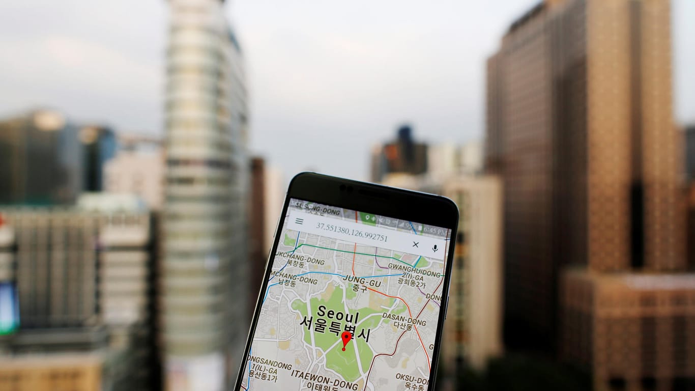 Smartphone mit Google Maps und Stadt im Hintergrund