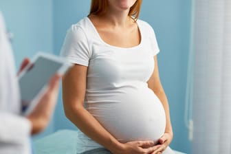 Eine Schwangere sitzt im Behandlungszimmer eines Arztes: Nabelschnurpunktion ist ein Verfahren der Pränataldiagnostik. Sie wird recht selten durchgeführt.
