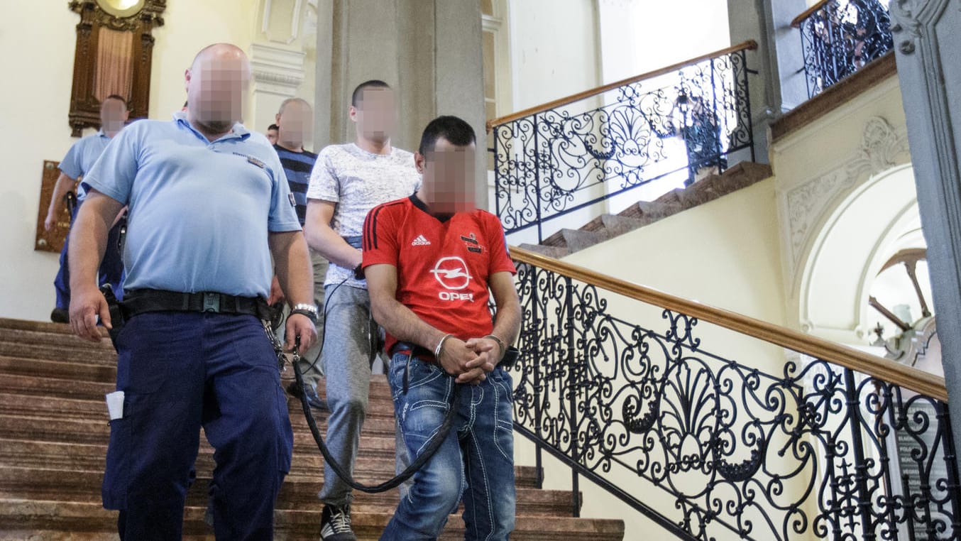 Unter schwerer Bewachung und in Handschellen werden zehn der elf Angeklagten aus dem Gerichtssaal geführt. Unter schwerer Bewachung und in Handschellen werden zehn der elf Angeklagten aus dem Gerichtssaal geführt.