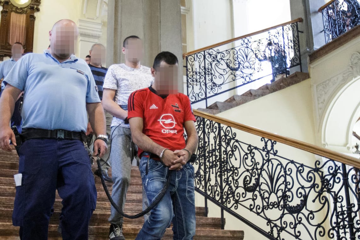 Unter schwerer Bewachung und in Handschellen werden zehn der elf Angeklagten aus dem Gerichtssaal geführt.