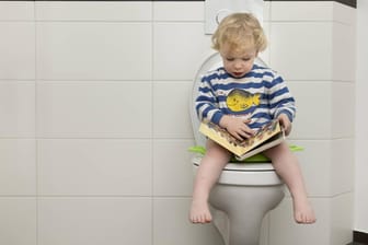 Kind sitzt auf der Toilette: Blähungen sollten Kinder nicht in aller Öffentlichkeit ausleben.