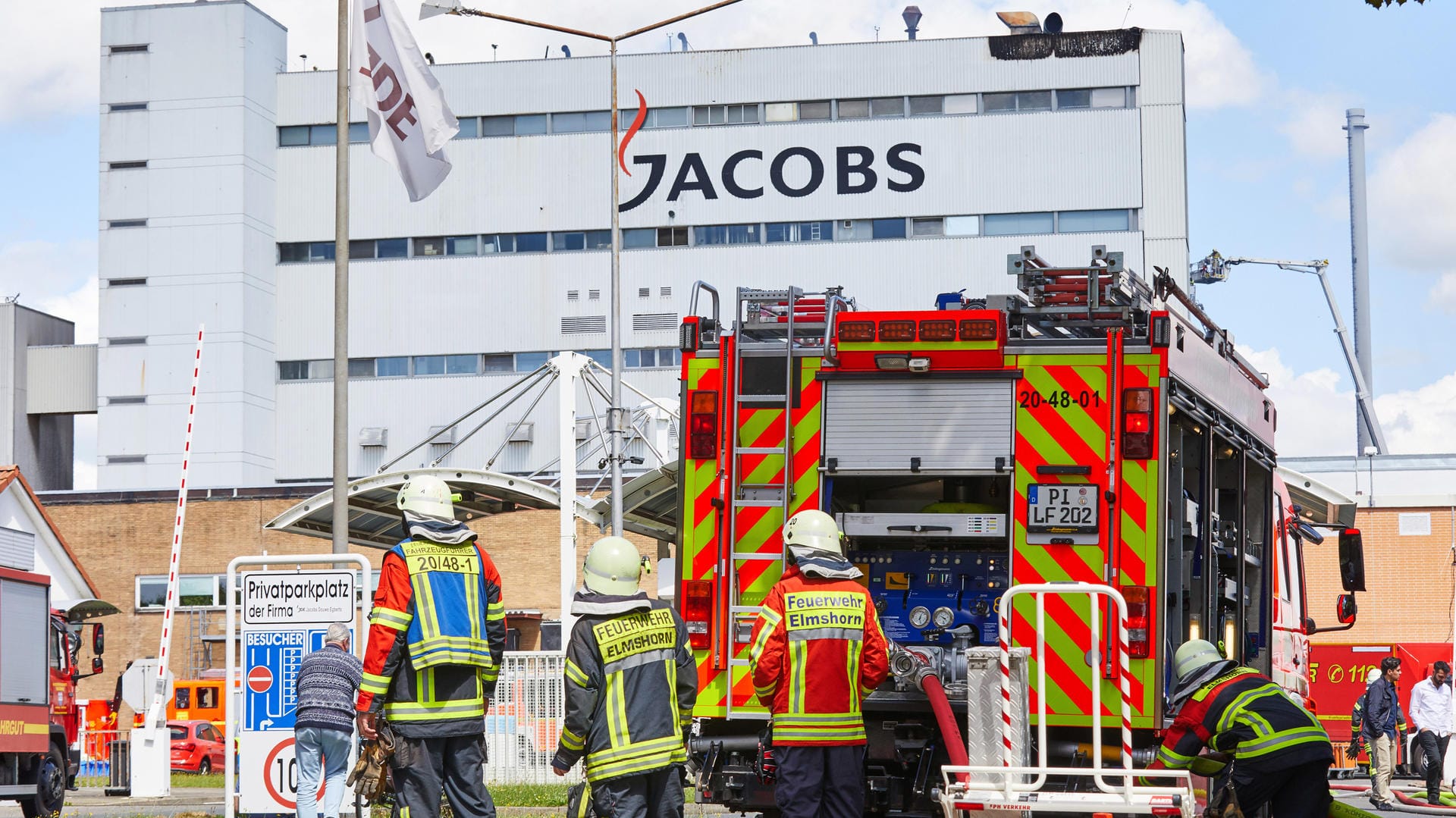 Feuerwehrmänner stehen vor dem Jacobs-Werk in Elmshorn.