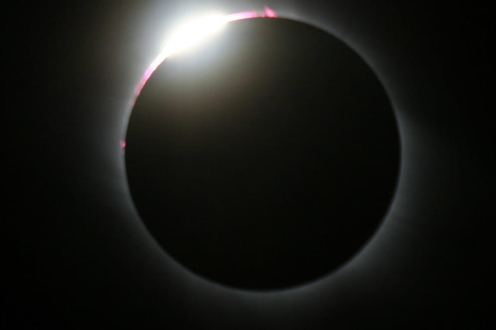 Eine totale Sonnenfinsternis tritt ein, wenn der Mond die Sonne komplett verdeckt und sein Kernschatten auf die Erde fällt.