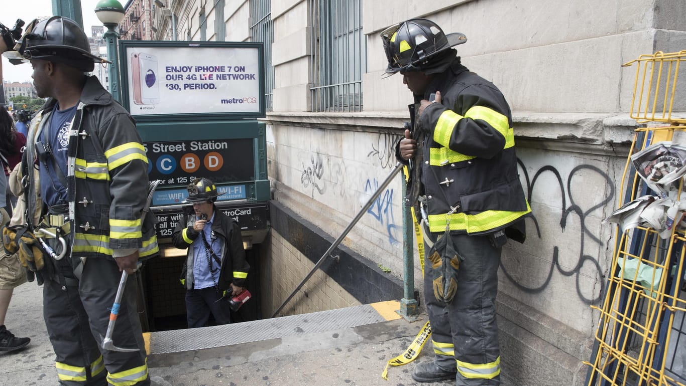 Feuerwehrmänner stehen vor einer U-Bahn Station im New Yorker Stadtteil Harlem.