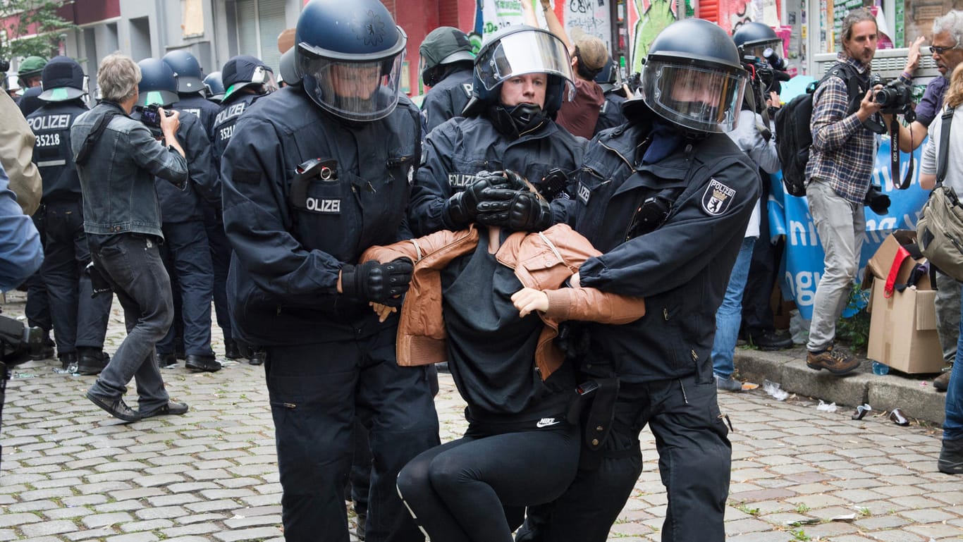 Polizisten tragen Demonstranten auf der Friedelstraße in Neukölln weg.