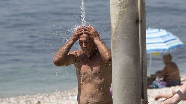 Ein Mann kühlt sich am Strand des Athener Vororts Alimos unter einer Dusche ab. Ein Mann kühlt sich am Strand des Athener Vororts Alimos unter einer Dusche ab.