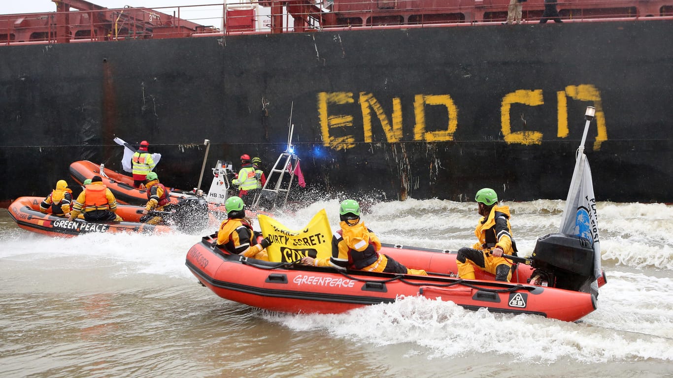 Greenpeace-Aktivisten fahren neben einem Kohlefrachter im Hamburger Hafen.