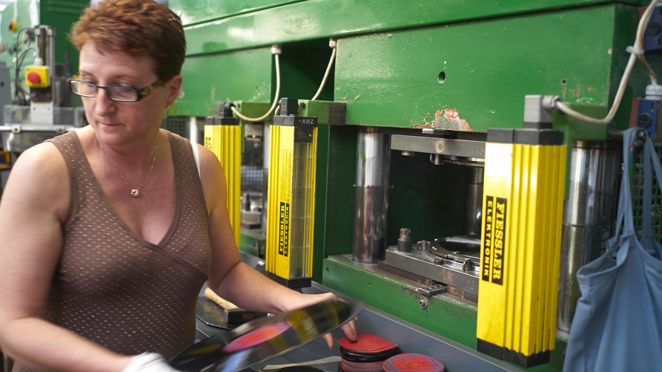 Eine Arbeiterin entnimmt eine frisch gespresste Schallplatte aus der Maschine in der Schallplattenfabrik GZ Media im tschechischen Lodenice.