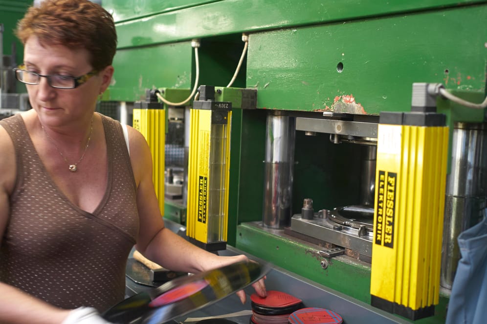 Eine Arbeiterin entnimmt eine frisch gespresste Schallplatte aus der Maschine in der Schallplattenfabrik GZ Media im tschechischen Lodenice.