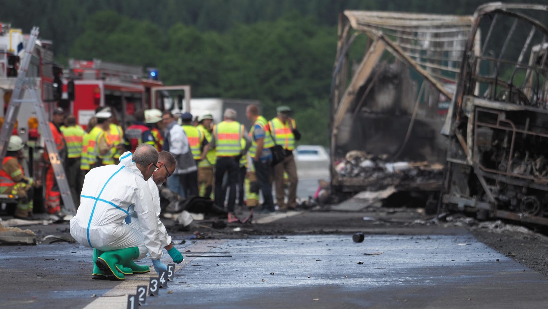 Experten der Polizei arbeiten an der Unfallstelle auf der Autobahn A9 neben dem Gerippe eines Busses und des Anhängers eines Lkw.