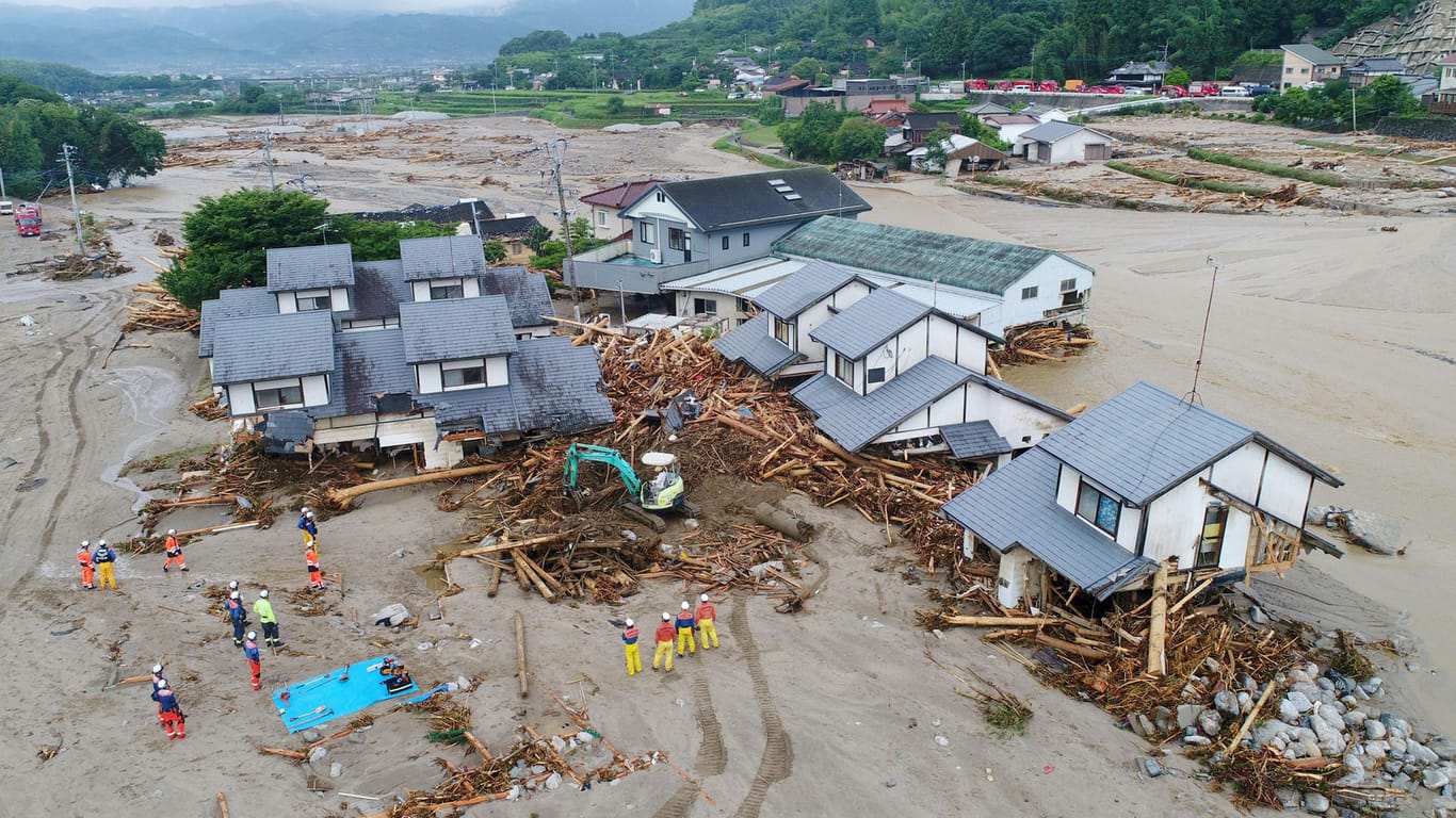 Rettungskräfte untersuchen die beschädigten Häuser in Asakura.