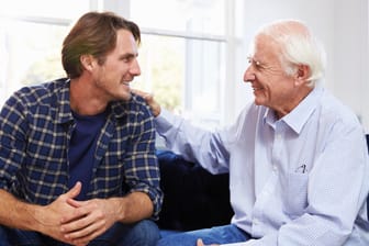 Ein junger und ein alter Mann sitzen auf dem Sofa