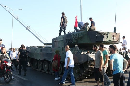 Türkische Polizisten und Anhänger von Präsident Erdogan stehen nach dem gescheiterten Putsch in der Nähe von Panzern auf der Bosporusbrücke in Istanbul.