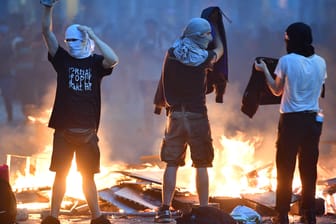 Aktivisten stehen im Schanzenviertel in Hamburg vor einer brennenden Barrikade.