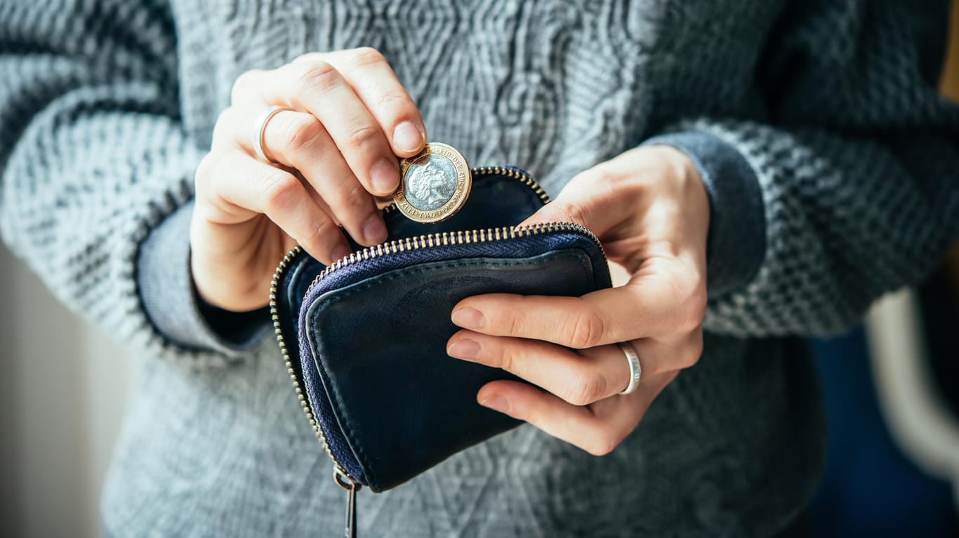 Eine Frau holt ein Geldstück aus ihrer Geldbörse