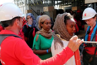 Mitarbeiter der Hilfsorganisation "Save the Children" helfen im Mittelmeer geretteten Flüchtlingen von Bord ihres Schiffes.