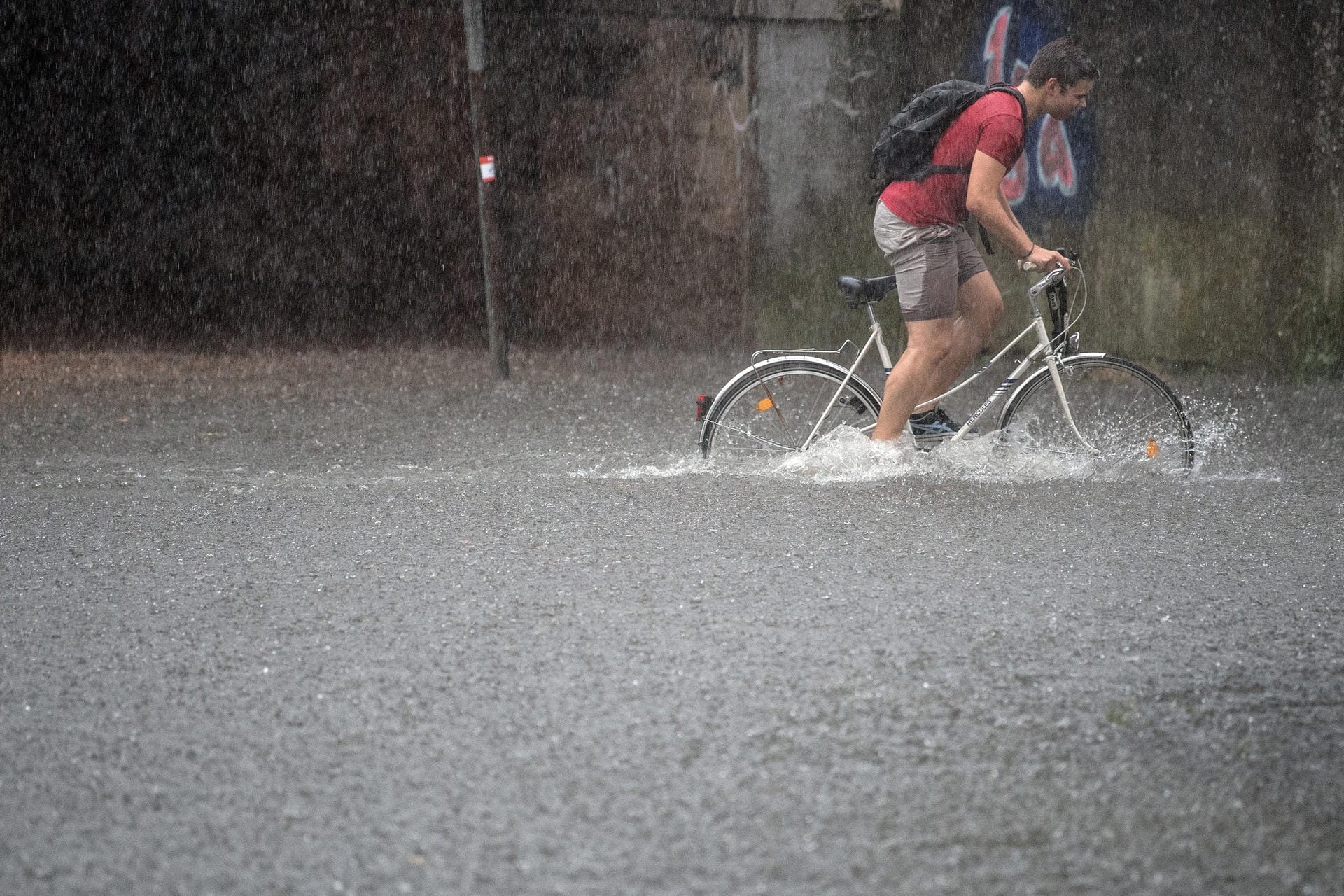 Ein Fahrradfahrer quält sich durch eine überflutete Straße in Köln. Ein Fahrradfahrer quält sich durch eine überflutete Straße in Köln.