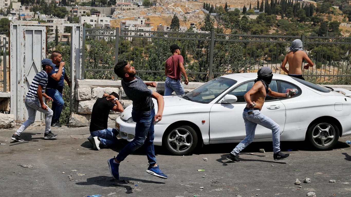 Palästinensische Jugendliche feuern Steine auf israelische Sicherheitskräfte.