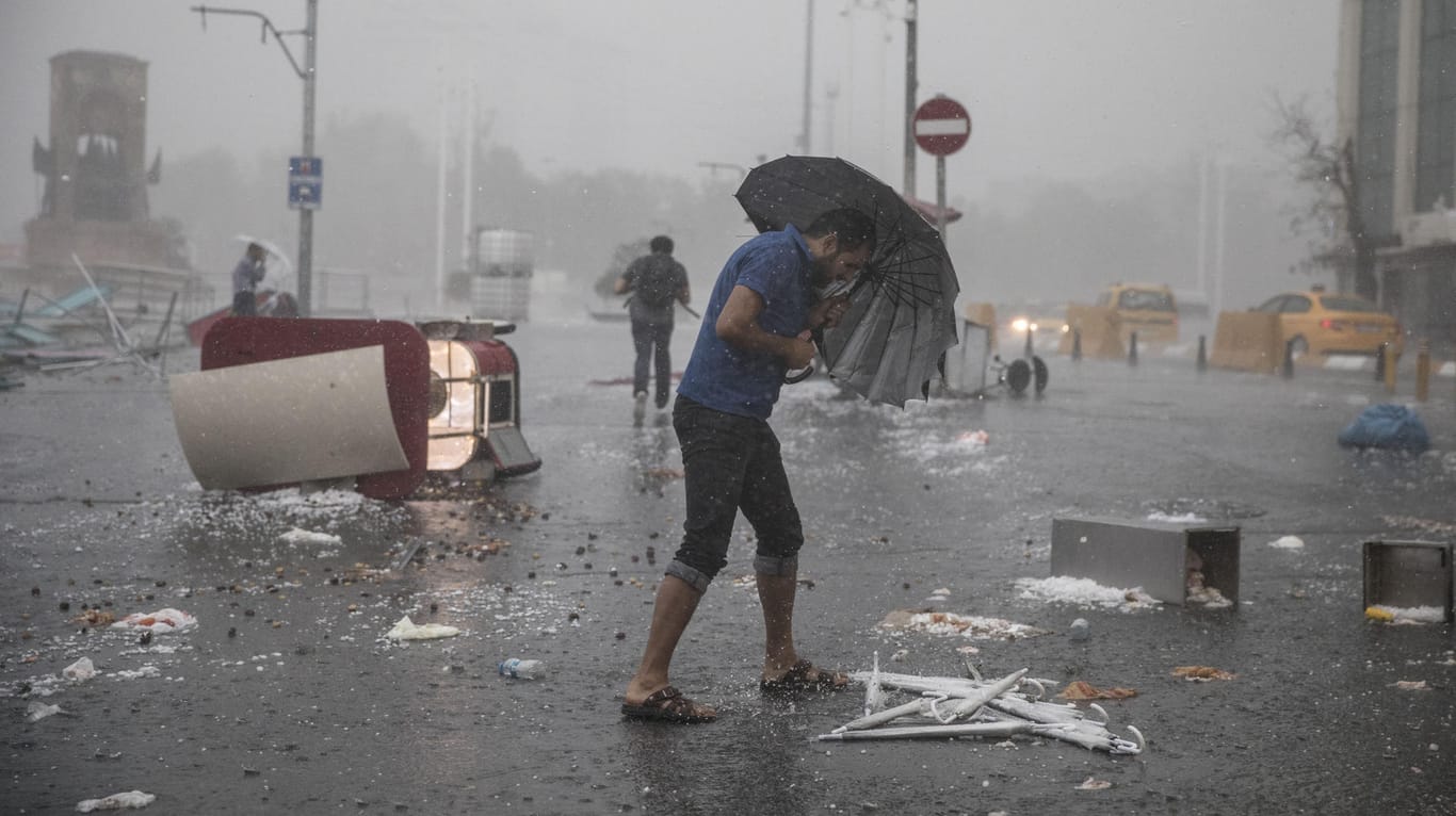 Ein Mann versucht sich auf dem Taksim-Platz vor dem Unwetter zu schützen.