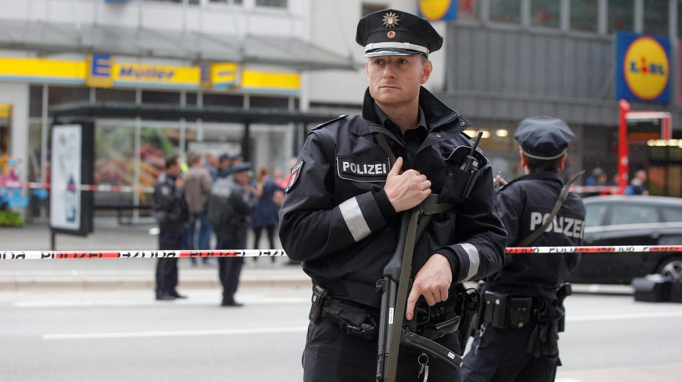 Ein schwerbewaffneter Polizist bewacht den Tatort im Hamburger Stadtteil Barmbek.