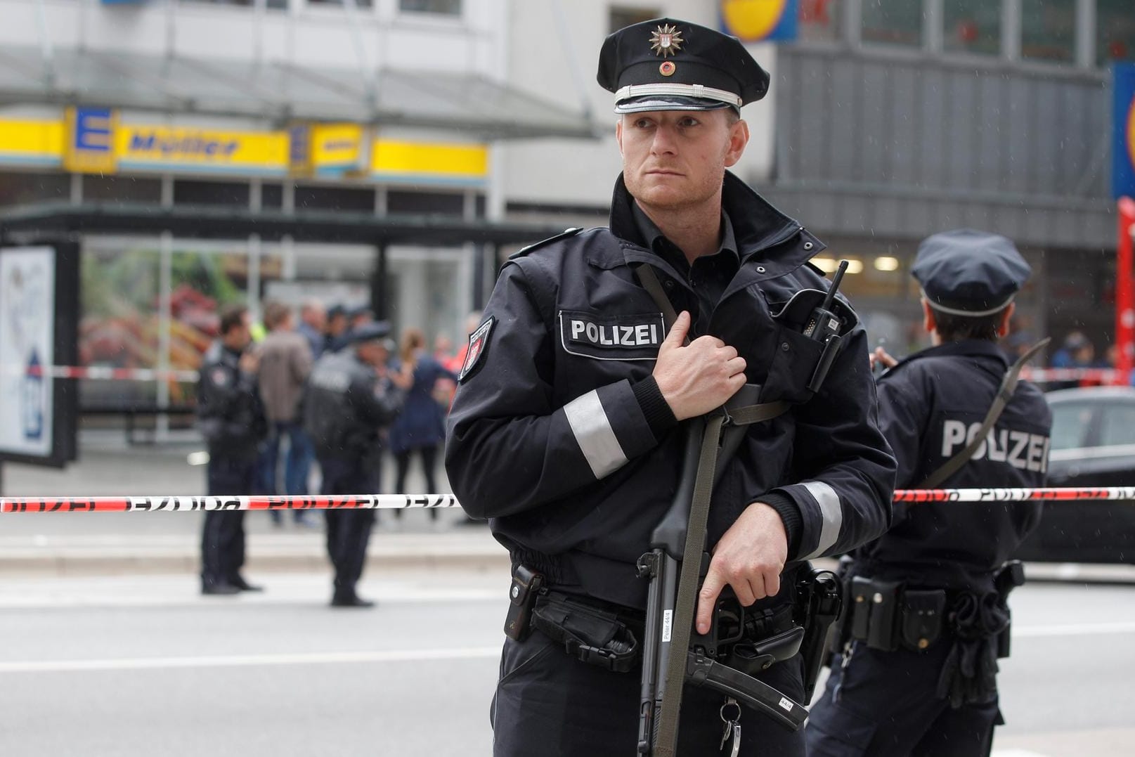 Ein schwerbewaffneter Polizist bewacht den Tatort im Hamburger Stadtteil Barmbek.