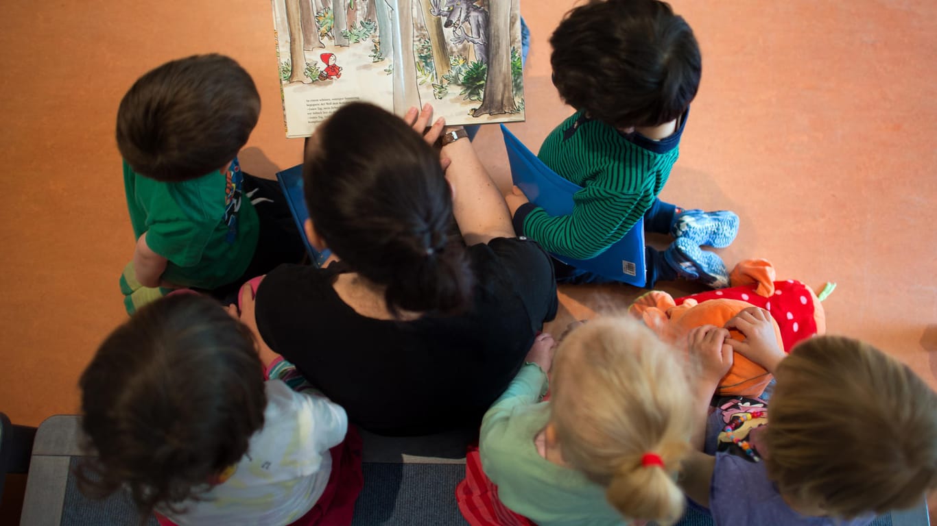 Eine pädagogische Fachkraft liest Kindern aus einem Buch vor.