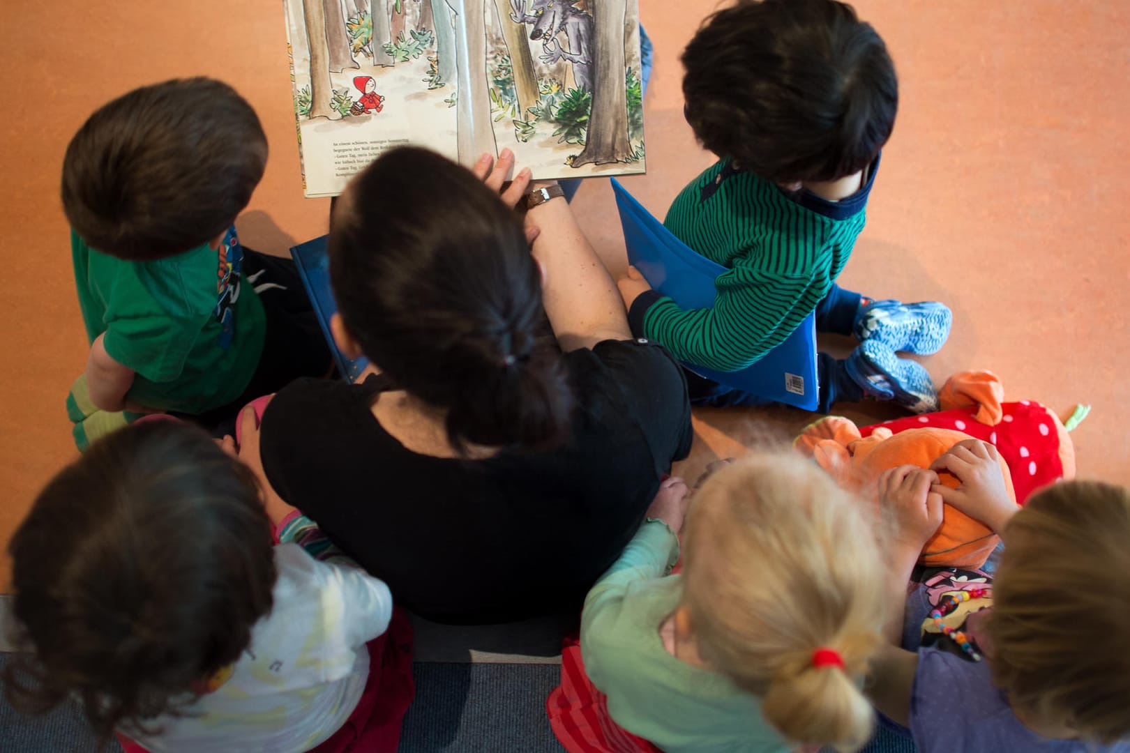 Eine pädagogische Fachkraft liest Kindern aus einem Buch vor.