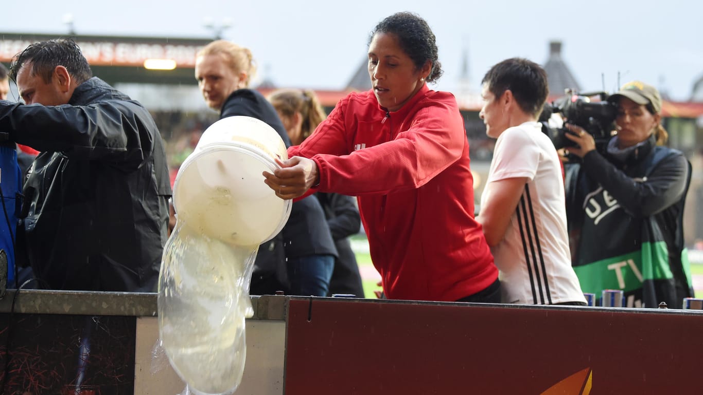 Land unter in Rotterdam: Bundestrainerin Steffi Jones hilft beim Entwässern der Ersatzbänke – am Ende vergeblich.