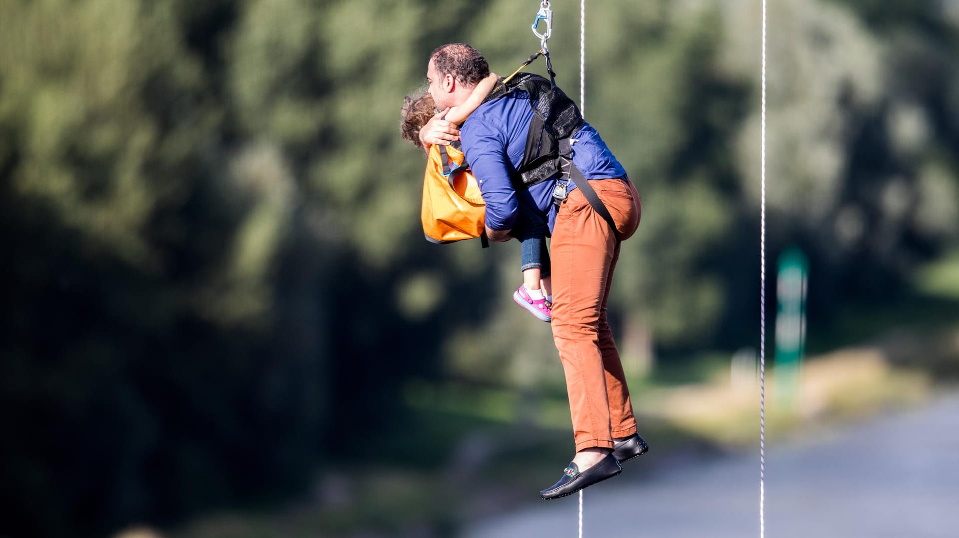 Ein Mann und ein kleines Kind werden aus einer Gondel abgeseilt.